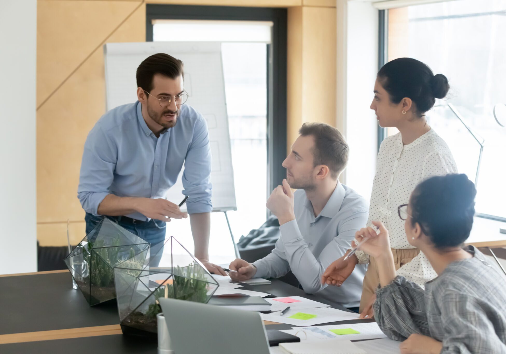Diverse colleagues employees team with leader brainstorming, gathering in boardroom, coworkers discussing financial documents, project results statistics, involved in briefing, sitting at table